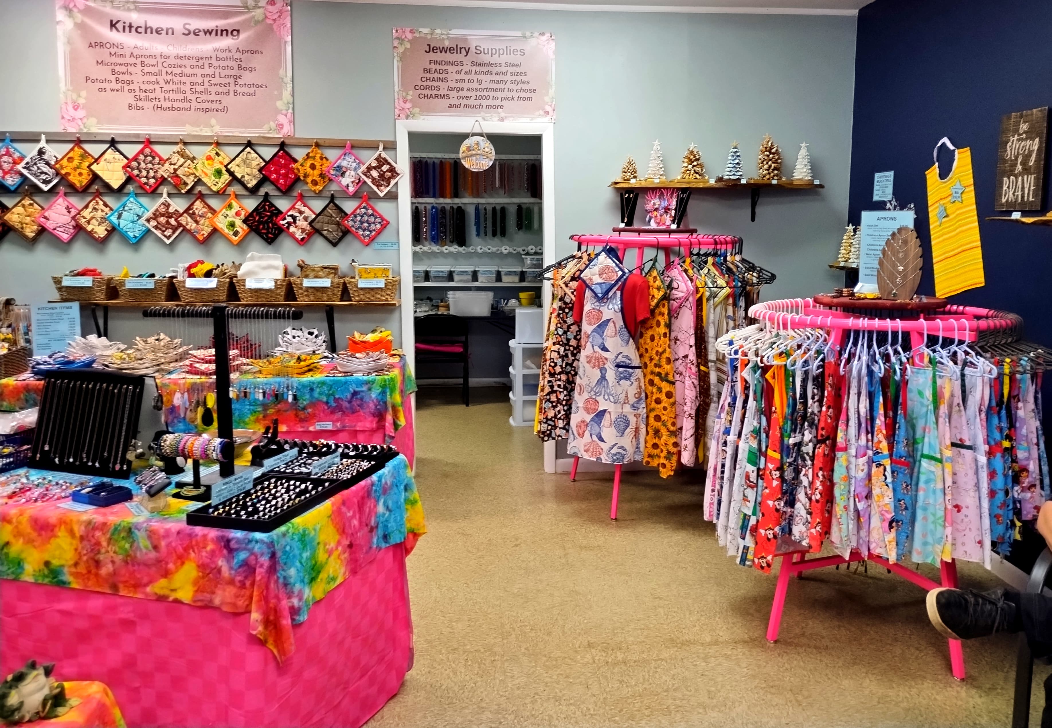 Colorful craft shop interior with racks of patterned aprons and displays of handmade jewelry.
