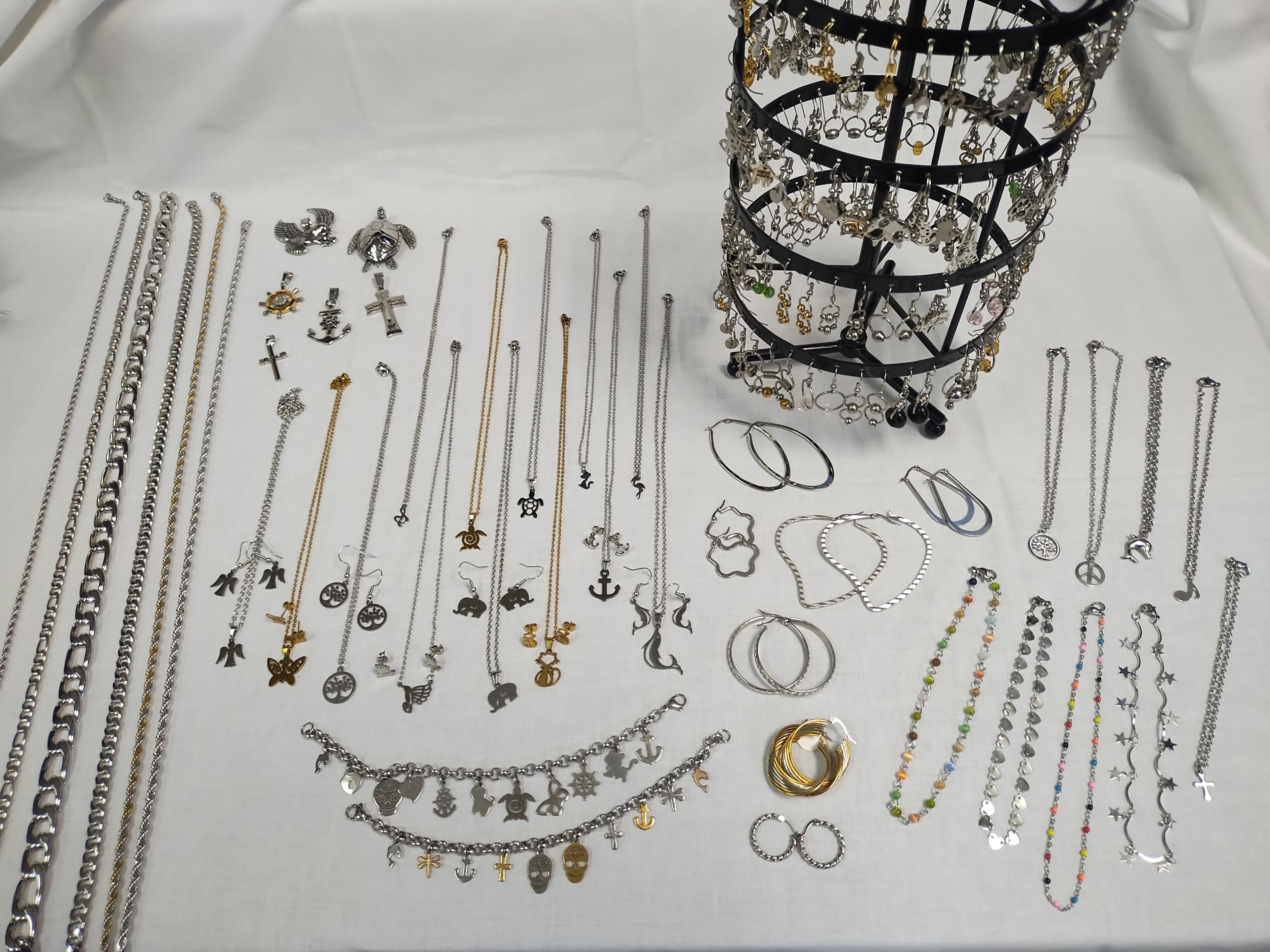 Assorted silver and gold jewelry, including necklaces, earrings, and bracelets, displayed on a white surface.